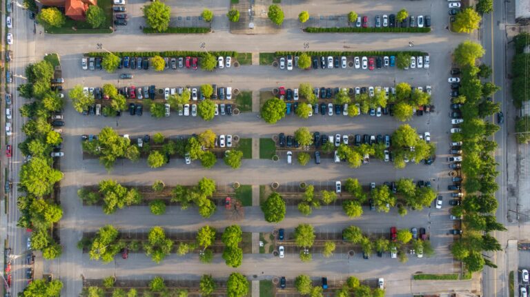 Drone shot of a parking lot in Chattanooga, TN, showcasing rows of parked cars and lush green trees.